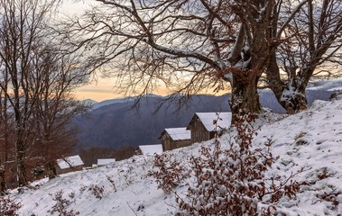 shepherds' houses in the winter Carpathians through the fog through which the sun breaks. Bad...