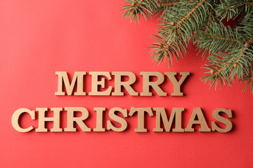 Fototapeta na wymiar The inscription Merry Christmas and Christmas tree branches. gold letters on a red background. holidays. Christmas.