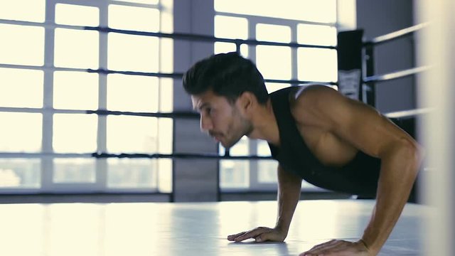 Sporty man doing push up exercise at the poxing ring.
