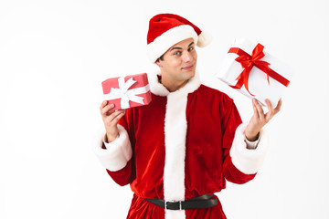 Portrait of kind man 30s in santa claus costume and red hat holding gift boxes, isolated on white background in studio