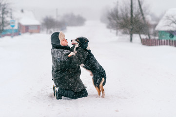 Fototapeta na wymiar Country woman. Adult female walking the dog. Funny winter girl lifestyle outdoor portrait. Comic lady love her puppy. Owner playing with pet in snow. Loving couple. Domestic animal - human`s friend.
