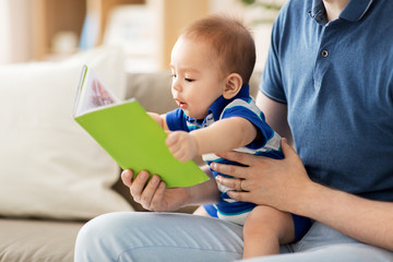 family, parenthood and people concept - happy asian baby boy and father with book at home