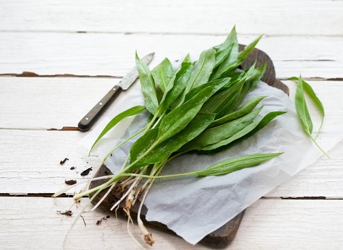 Fresh wild garlic on paper and a wooden chopping board