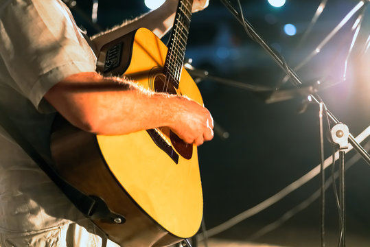 Man playing yellowe an acoustic guitar closeup