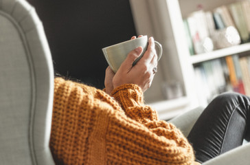 Junge Frau entspannt mit einer Tasse Tee im Sessel