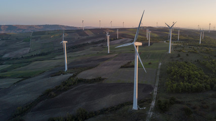 Aerial view at sunset of Wind turbines for renewable sources of electricity without pollution. These sustainable eco-friendly structures are built in the mountains of Irpinia, in Italy.
