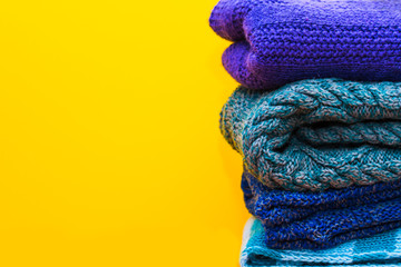 stack of knitted clothes on yellow background
