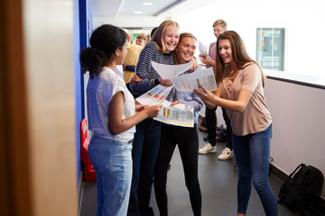Excited Teenage High School Students Celebrating Exam Results In School Corridor