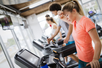 Young and beautiful lady running on a treadmill and sweating