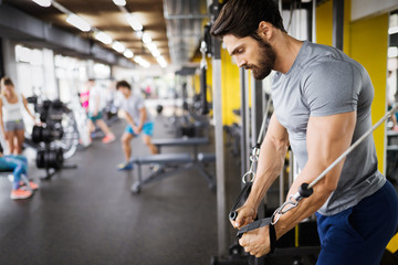 Young handsome man doing exercises in gym