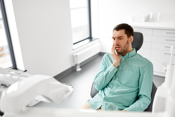 Fototapeta premium medicine, dentistry and healthcare concept - male patient suffering from toothache at dental clinic office