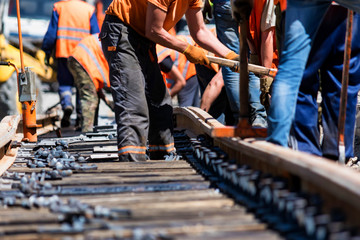 Workers in bright uniforms lay railway or tram tracks