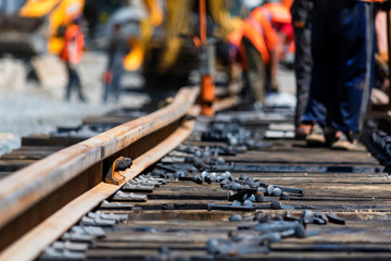 Workers in bright uniforms lay railway or tram tracks