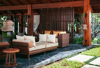 Resort style couch, wood table with fabric cusion and pillow under wooden pavilion