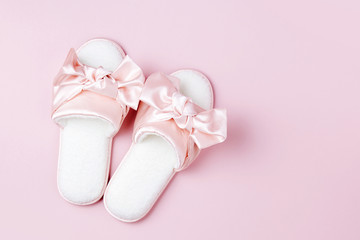 Stylid female slippers with bow on pale pink  background. Flat lay, top view
