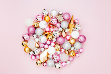 Holiday round arrangement with Stylish Christmas shiny balls and gold crystals on pastel pink background. Flat lay, top view