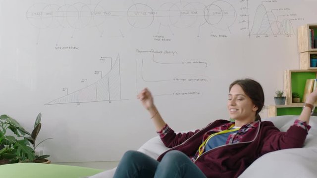 happy caucasian woman student jumping on colorful pillows relaxing female resting enjoying lunch break in trendy office workplace