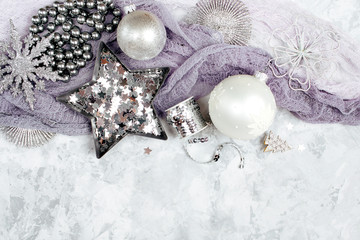 Christmas decorations, bows, stars in silver colour on grey background. Holiday and celebration. Flat lay, top view