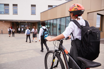 Group Of High School Students Wearing Uniform Arriving At School Walking Or Riding Bikes