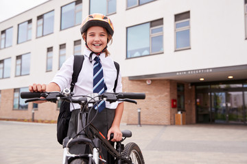 Portrait Of Female High School Student Wearing Uniform With Bicycle Outside School Buildings
