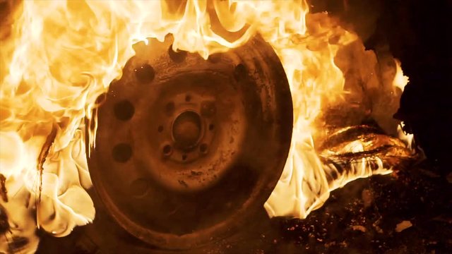 A wheel burns in a car at night, car tires burn, close-up
