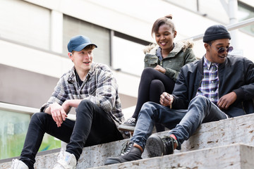 Fototapeta premium Group of young friends sitting on staircase making fun