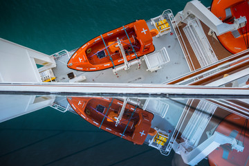 Cruise ship side with lifeboats and balcony.