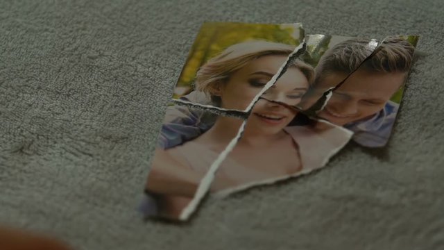 Male hands connecting tearing pieces of photo with his girlfriend, yearning