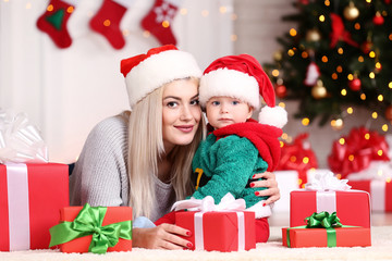 Fototapeta na wymiar Mother and son in santa hats celebrate christmas at home