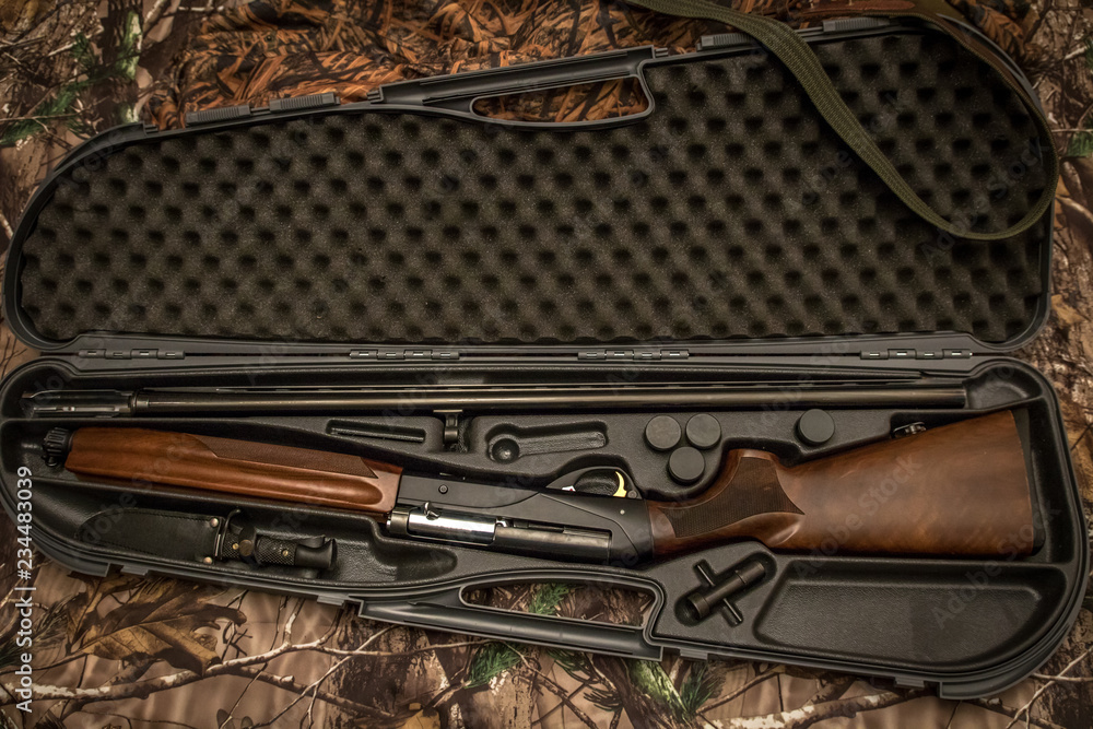 Wall mural disassembled shotgun parts in the gun case on the camouflage background