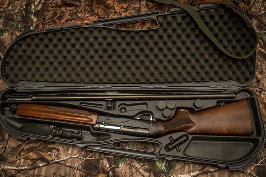 disassembled shotgun parts in the gun case on the camouflage background