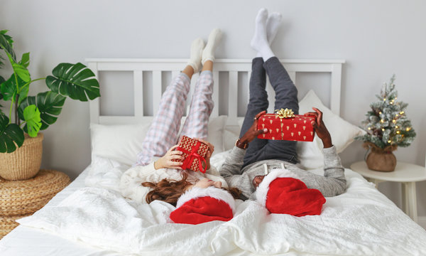 happy young couple with gifts on Christmas morning in bed