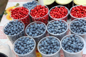 Blueberries and cranberries on the counter in plastic cups
