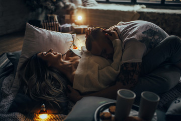 Young couple hugging and smiling on background of glowing lightbulbs.