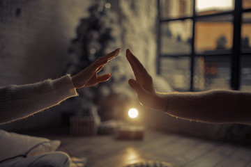 Male and female hand touching each other against the background of light and window.