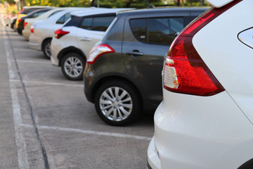 Closeup of rear side of white car parking in parking area beside the street in sunny day. 