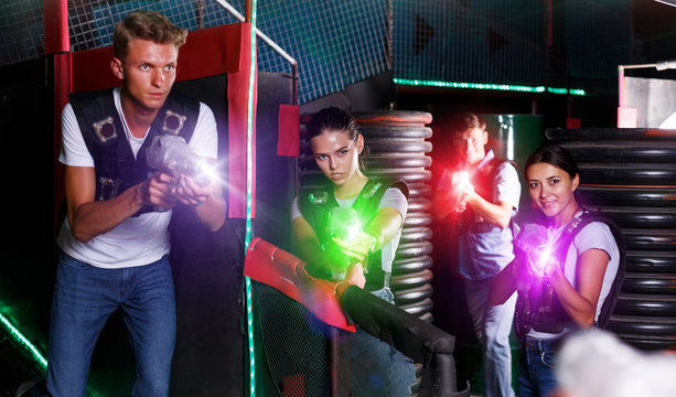 friends playing laser tag  game  with laser guns near tires