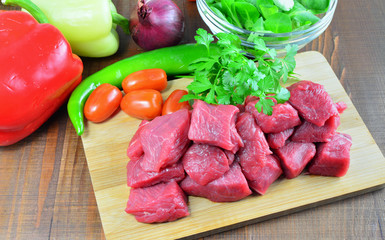 Meat cubes with vegetables and ingredients for cooking goulash or stew