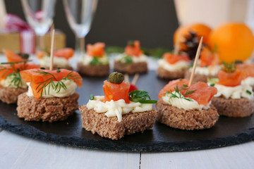 Smoked salmon canapes with cheese cream and capers on rye bread