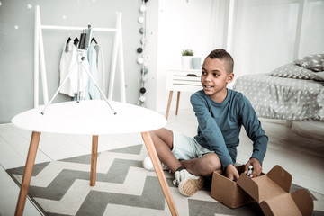 Online stream. Joyful positive boy sitting on the floor while streaming a video to his blog