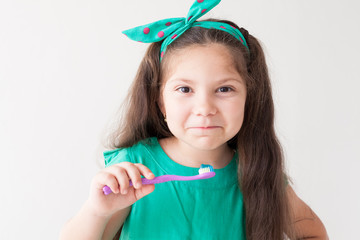 little girl brushing his teeth with a toothbrush dent