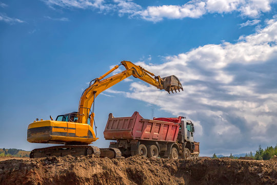 Yellow Excavator And Empty Dump Truck Working At The Construction Site