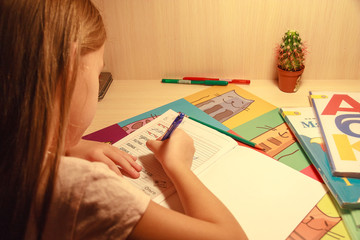 girl holding a pencil and writing in a notebook words and letters