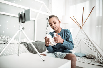 Dangerous predator. Positive nice boy holding a dinosaur skull model while recording a video for...