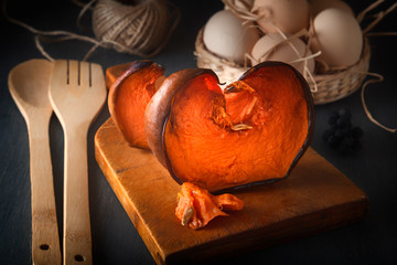 Slices of baked pumpkin with honey on a wooden board on the background of a wicker basket with eggs