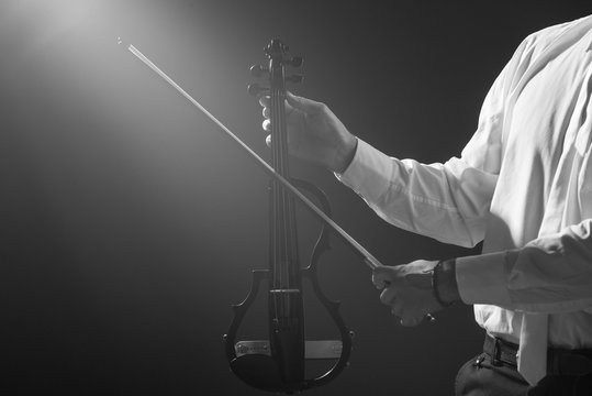 The musician holds a electronic violin in his hands      