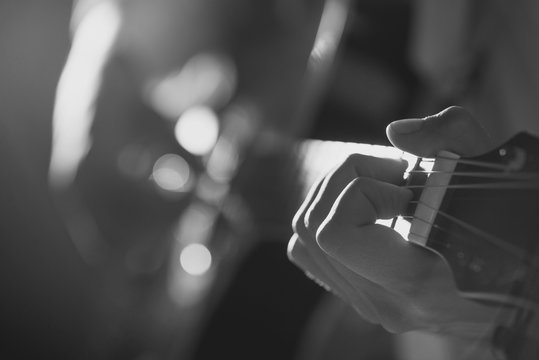 Musician plays guitar hands on strings close up. Theme music.