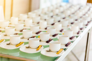 A lot of white coffee cups and brown sugar in the seminar with blurred background.