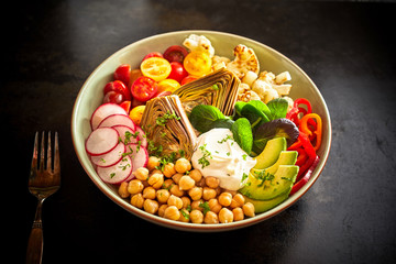 Bowl of raw vegetables on black table