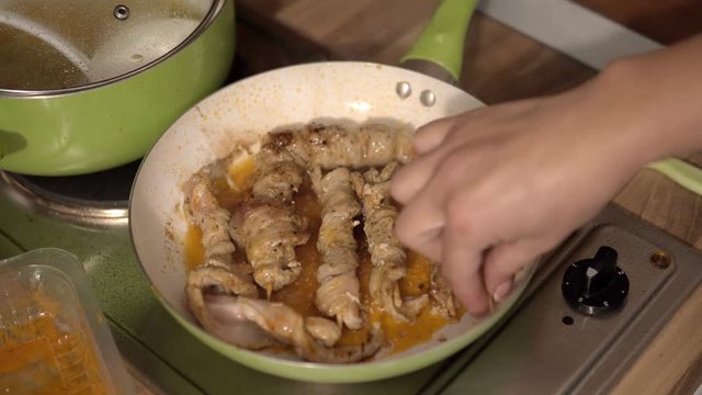 Juicy roasted chicken skewers; made of white meat and bacon; being turned in frying pan